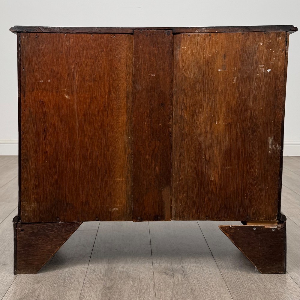 A small 20th-century Dutch bombe chest of drawers made from polished brown wood with three drawers, brass handles, and carved claw feet. View V