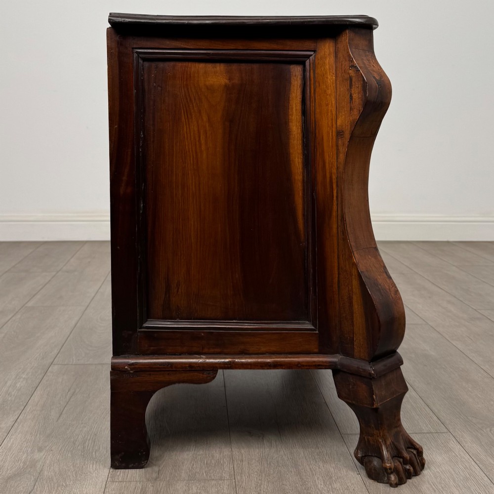 A small 20th-century Dutch bombe chest of drawers made from polished brown wood with three drawers, brass handles, and carved claw feet. View VII