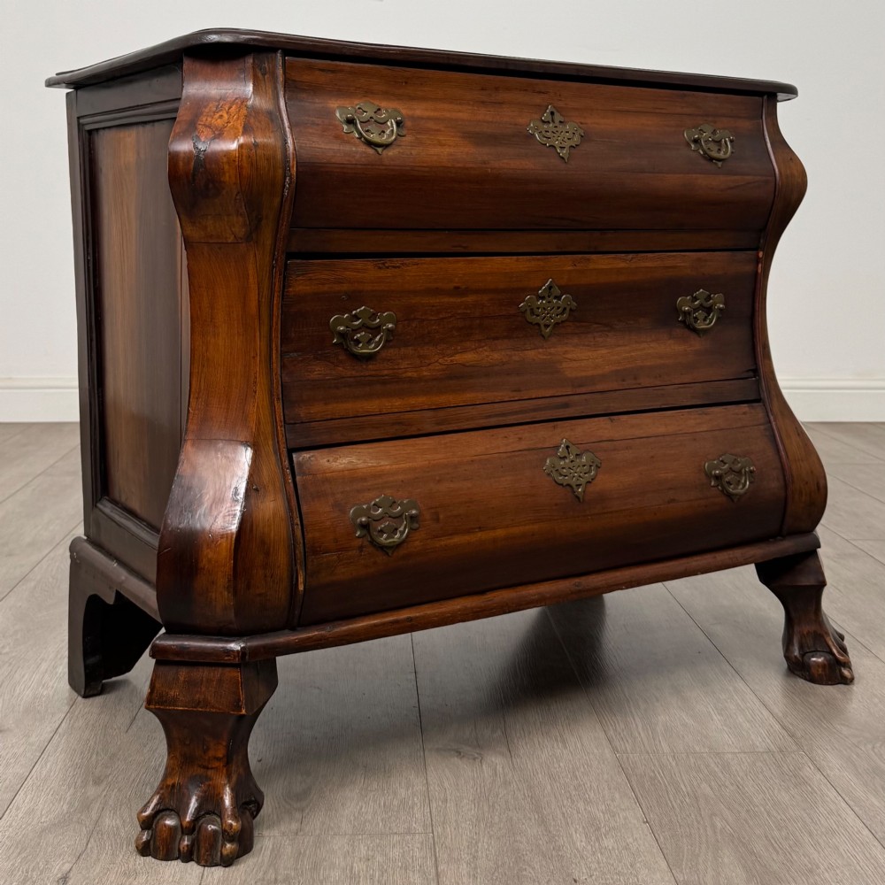 A small 20th-century Dutch bombe chest of drawers made from polished brown wood with three drawers, brass handles, and carved claw feet. View VIII