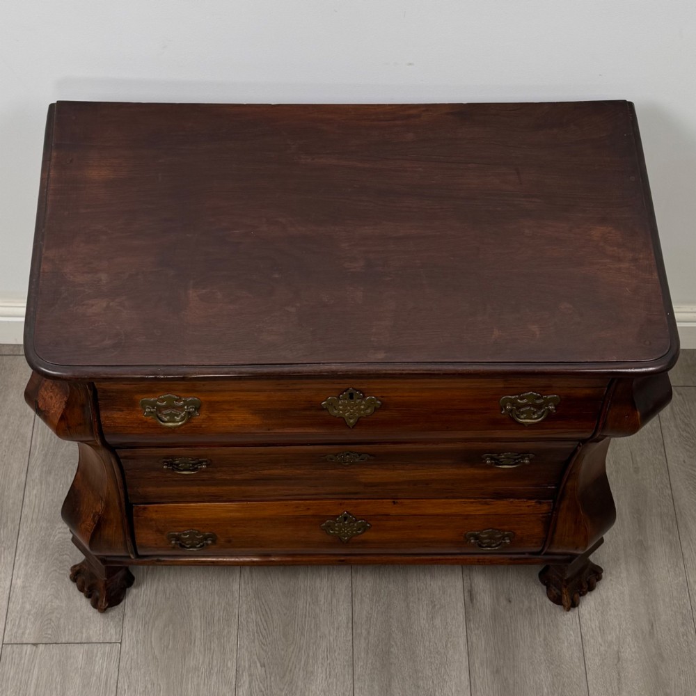 A small 20th-century Dutch bombe chest of drawers made from polished brown wood with three drawers, brass handles, and carved claw feet. View IX