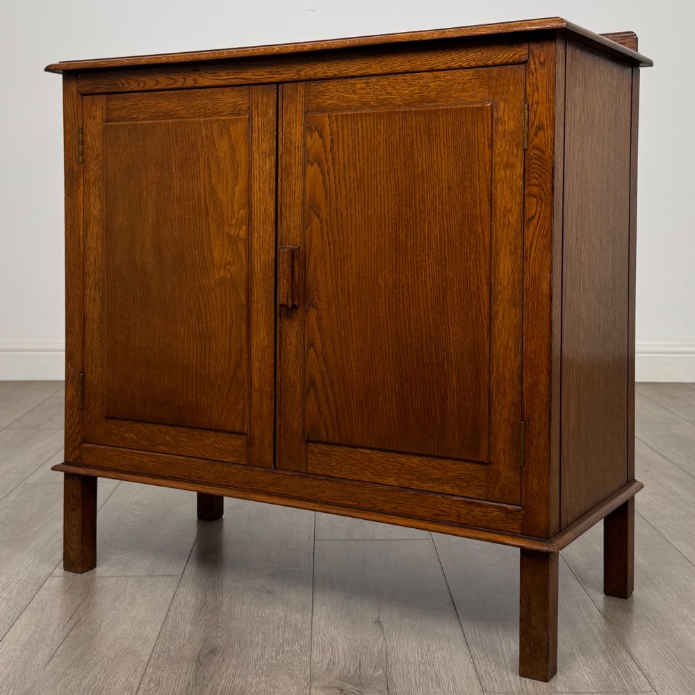 An Edwardian warm brown oak fitted cupboard featuring twin recessed panel doors, a central wooden latch, and four straight legs. View III