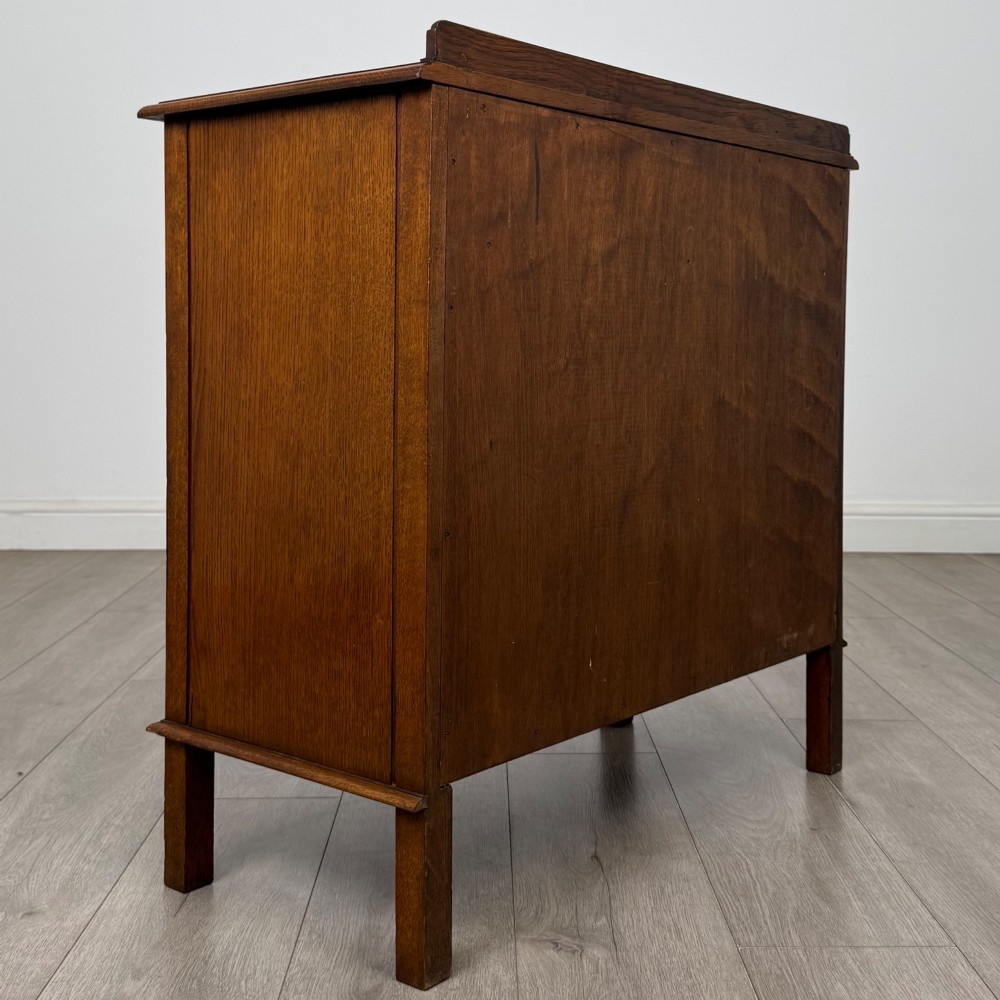An Edwardian warm brown oak fitted cupboard featuring twin recessed panel doors, a central wooden latch, and four straight legs. View V