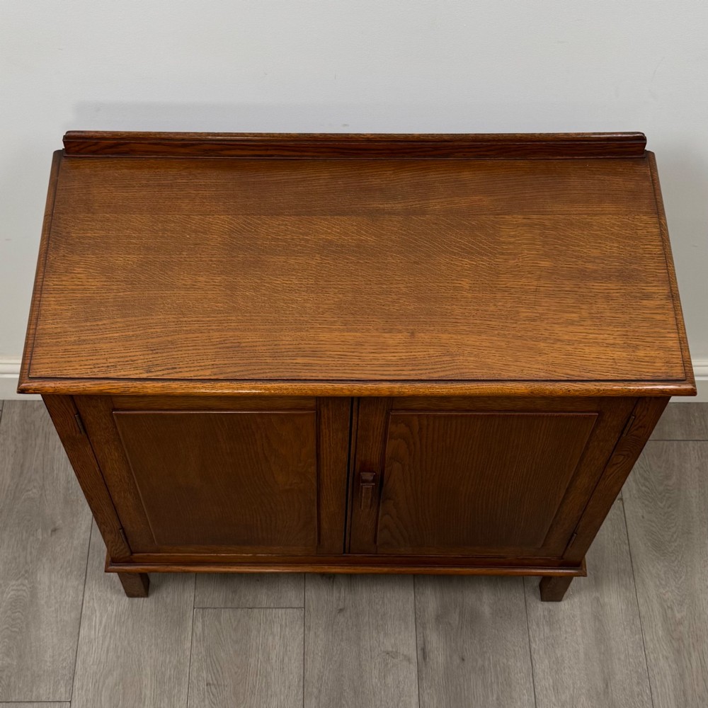 An Edwardian warm brown oak fitted cupboard featuring twin recessed panel doors, a central wooden latch, and four straight legs. View X