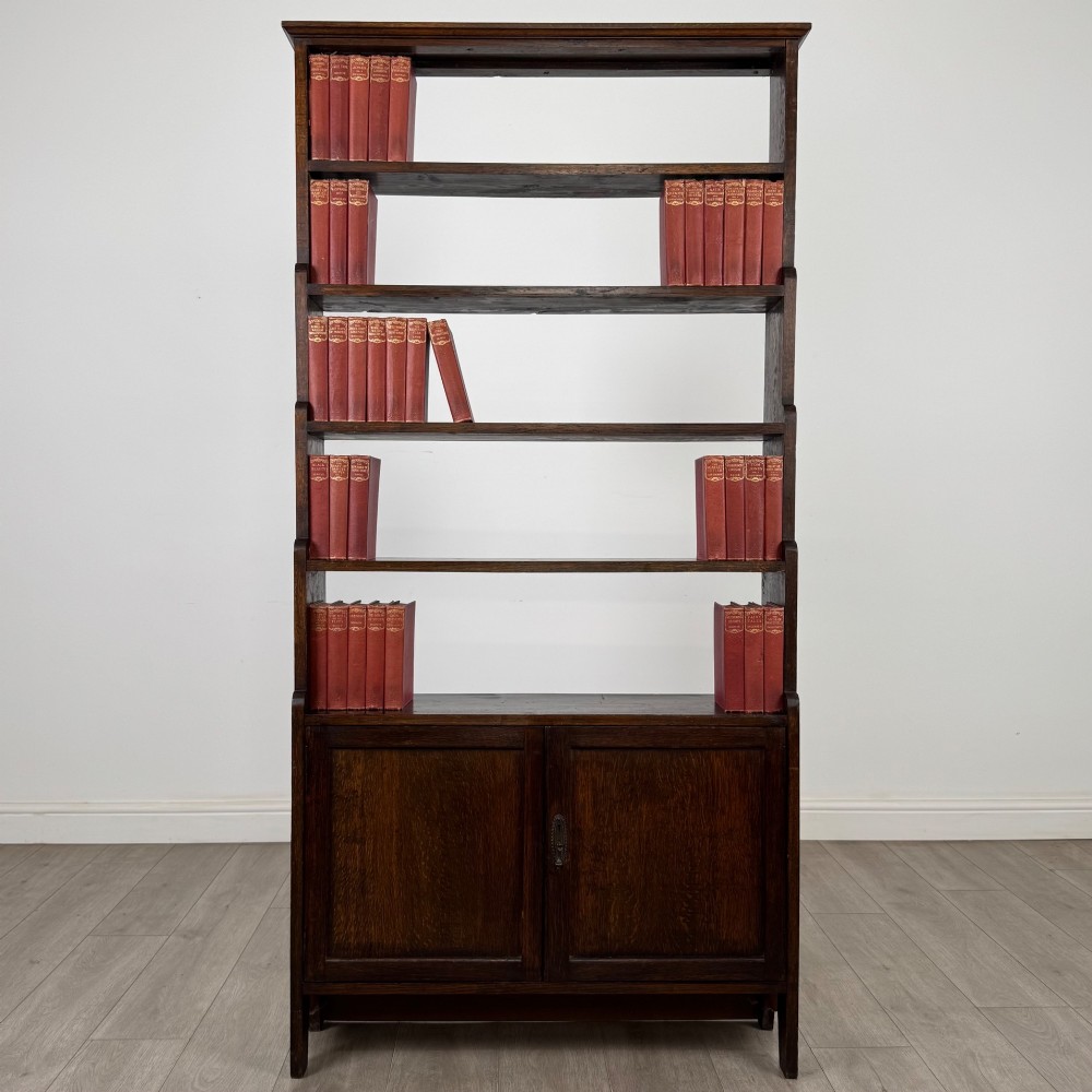 A tall dark oak open bookcase featuring multiple upper shelves and a two-door lower cupboard base.