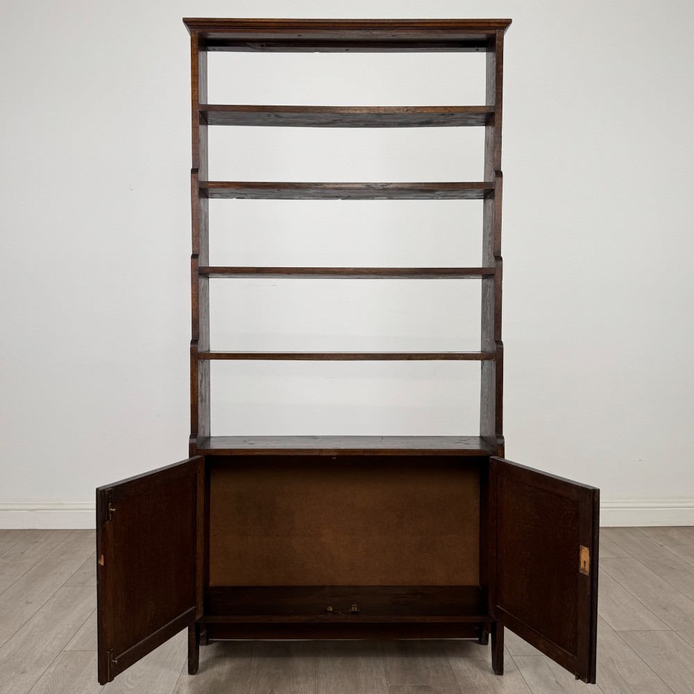 A tall dark oak open bookcase featuring multiple upper shelves and a two-door lower cupboard base. View III