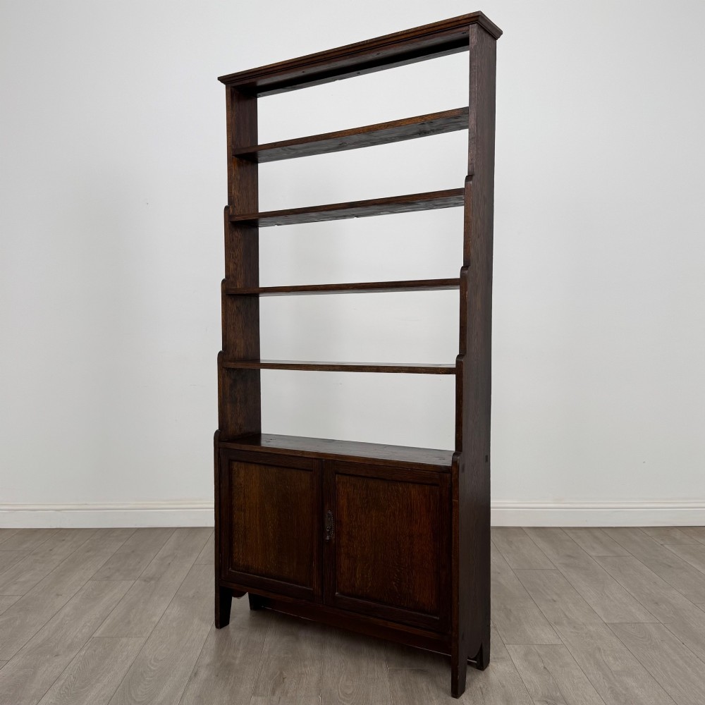 A tall dark oak open bookcase featuring multiple upper shelves and a two-door lower cupboard base. View IV