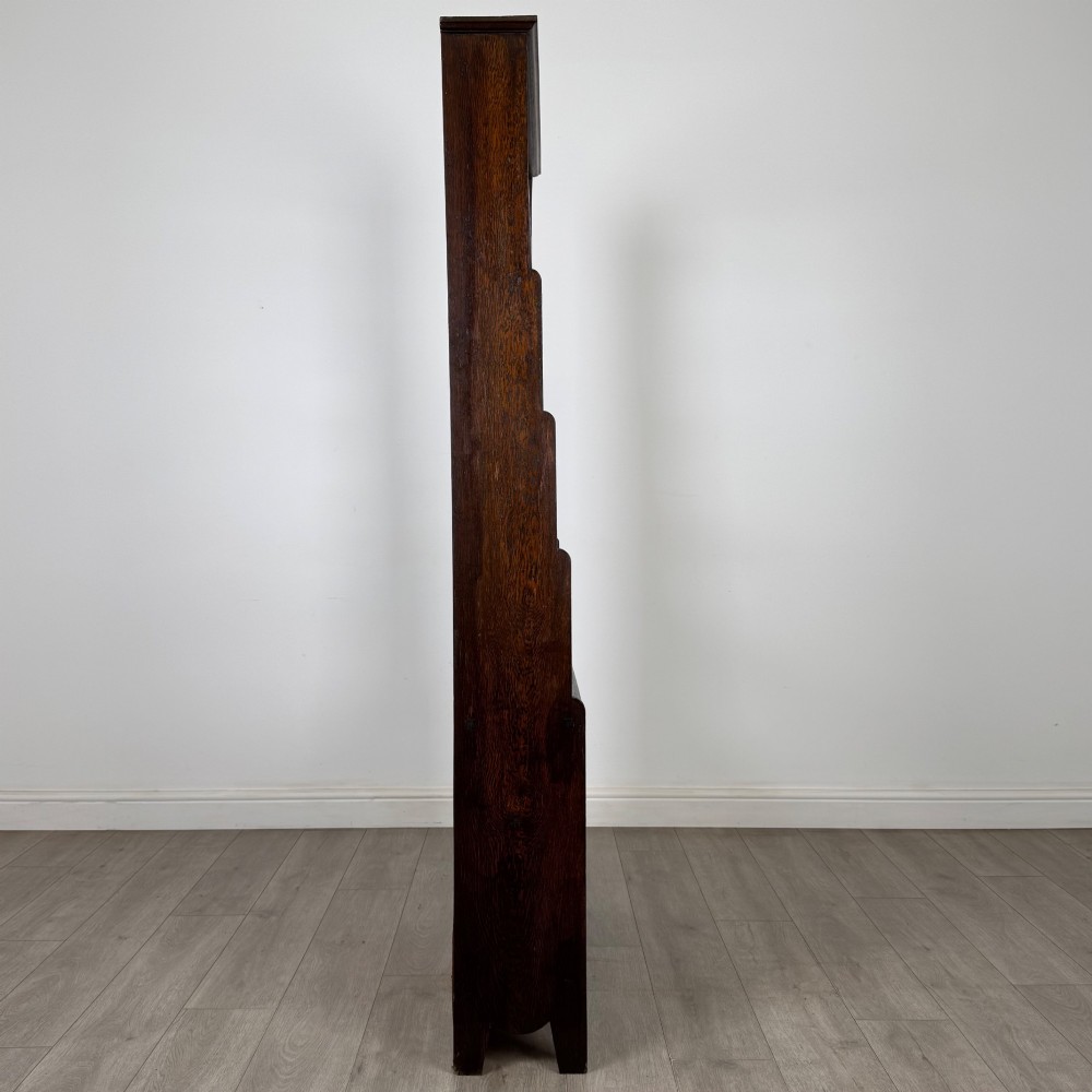 A tall dark oak open bookcase featuring multiple upper shelves and a two-door lower cupboard base. View IX