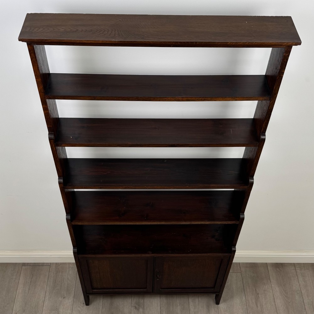 A tall dark oak open bookcase featuring multiple upper shelves and a two-door lower cupboard base. View XI
