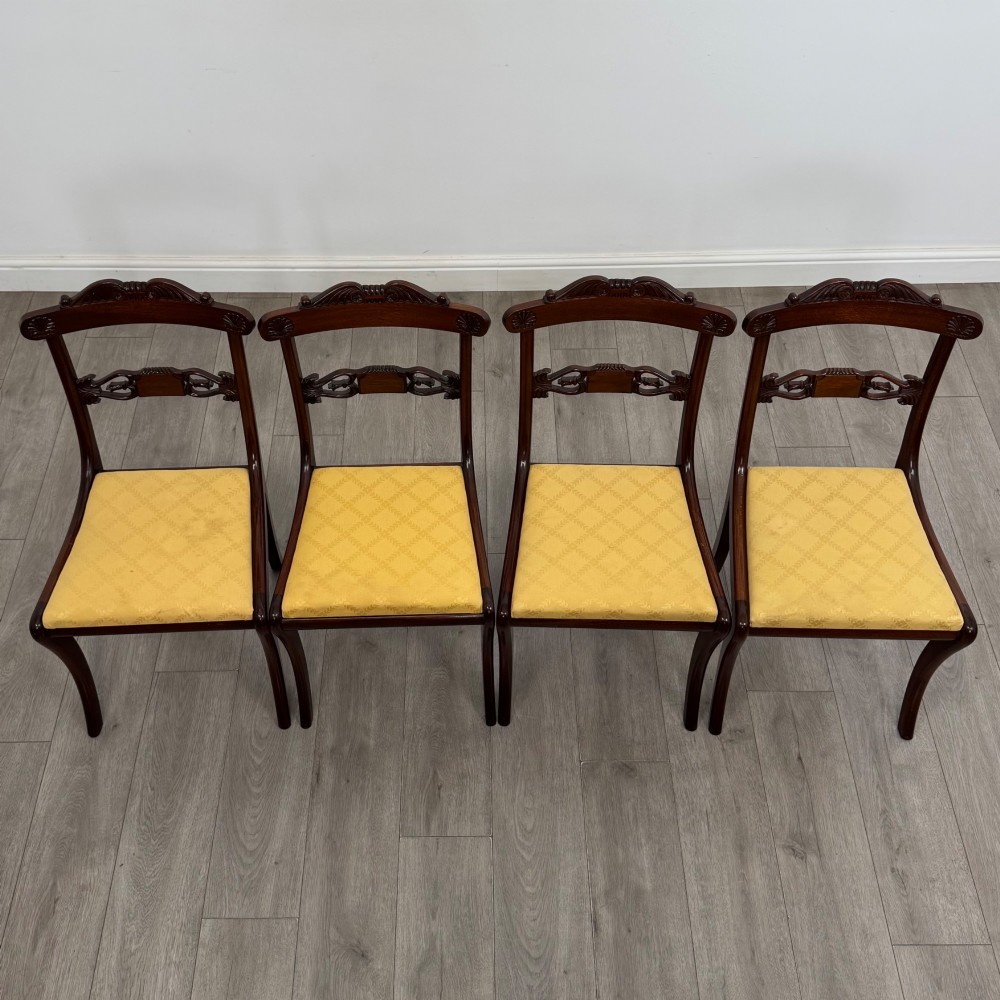 A set of ten mahogany Regency style dining chairs with yellow upholstered seats, including eight side chairs and two carvers with scrolling arms. View II