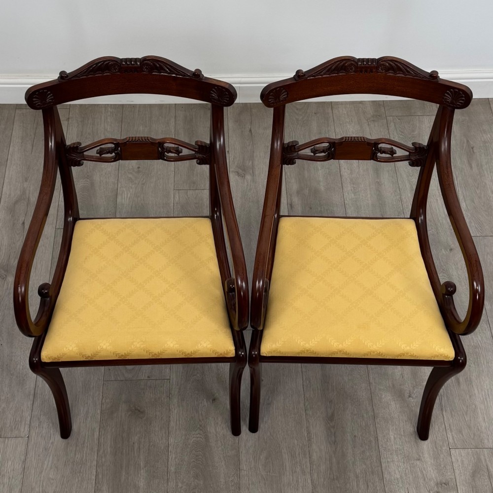 A set of ten mahogany Regency style dining chairs with yellow upholstered seats, including eight side chairs and two carvers with scrolling arms. View IV