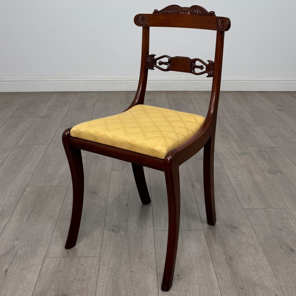 A set of ten mahogany Regency style dining chairs with yellow upholstered seats, including eight side chairs and two carvers with scrolling arms. View VI