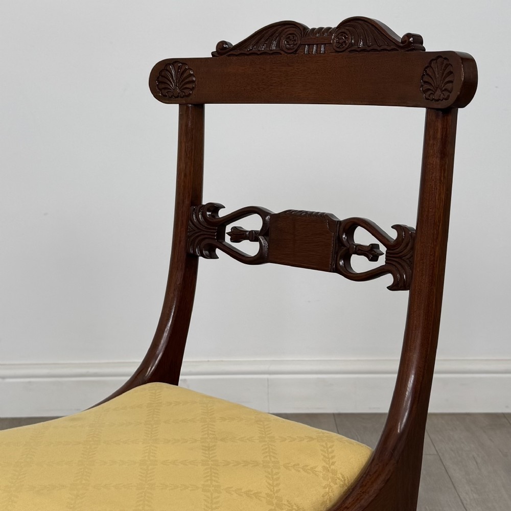 A set of ten mahogany Regency style dining chairs with yellow upholstered seats, including eight side chairs and two carvers with scrolling arms. View VII