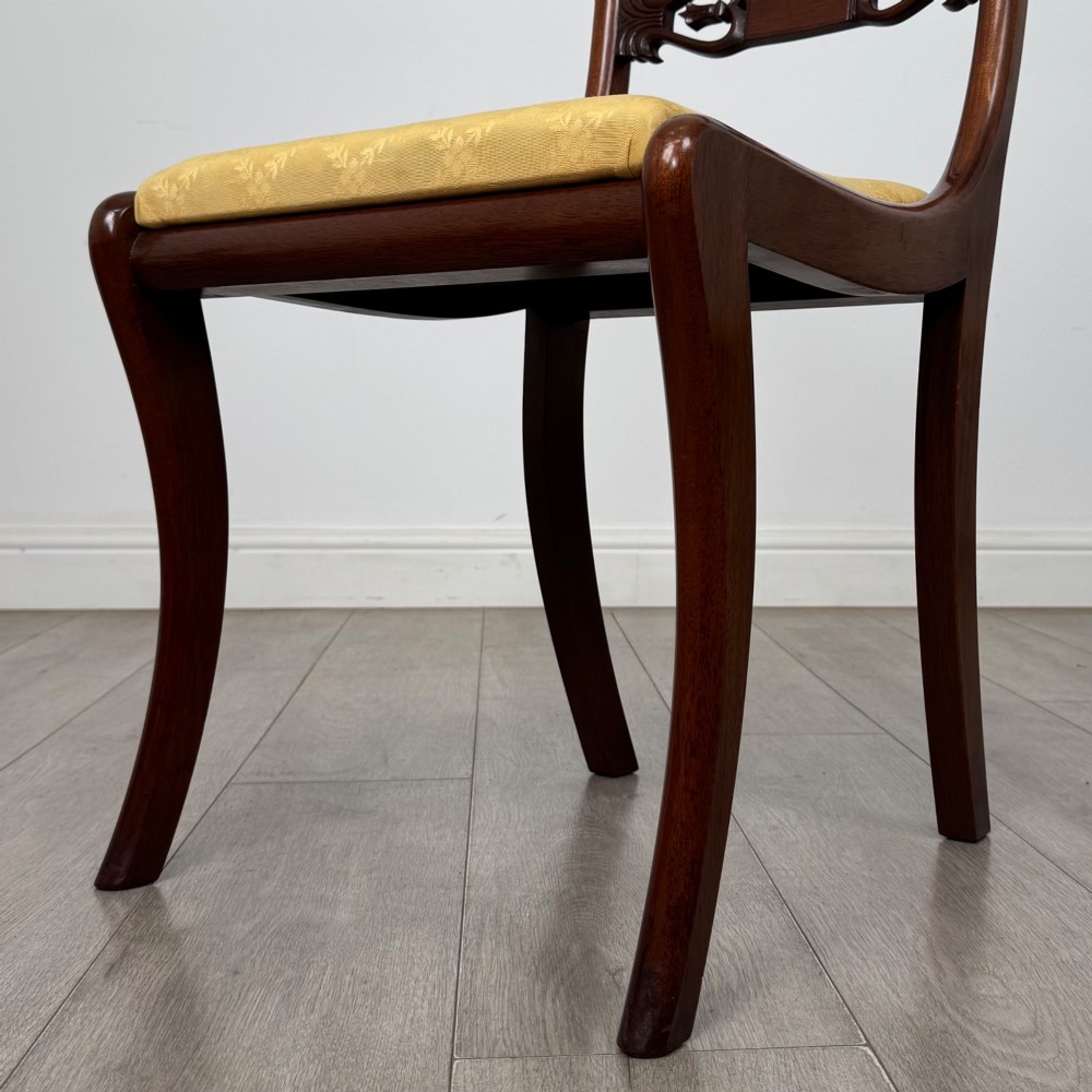 A set of ten mahogany Regency style dining chairs with yellow upholstered seats, including eight side chairs and two carvers with scrolling arms. View VIII