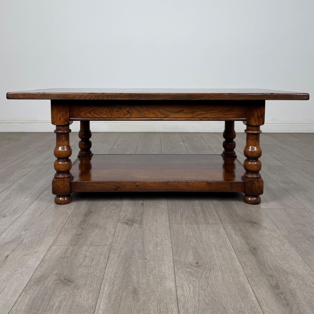 A rectangular dark oak coffee table featuring turned baluster legs and a full-length lower shelf.