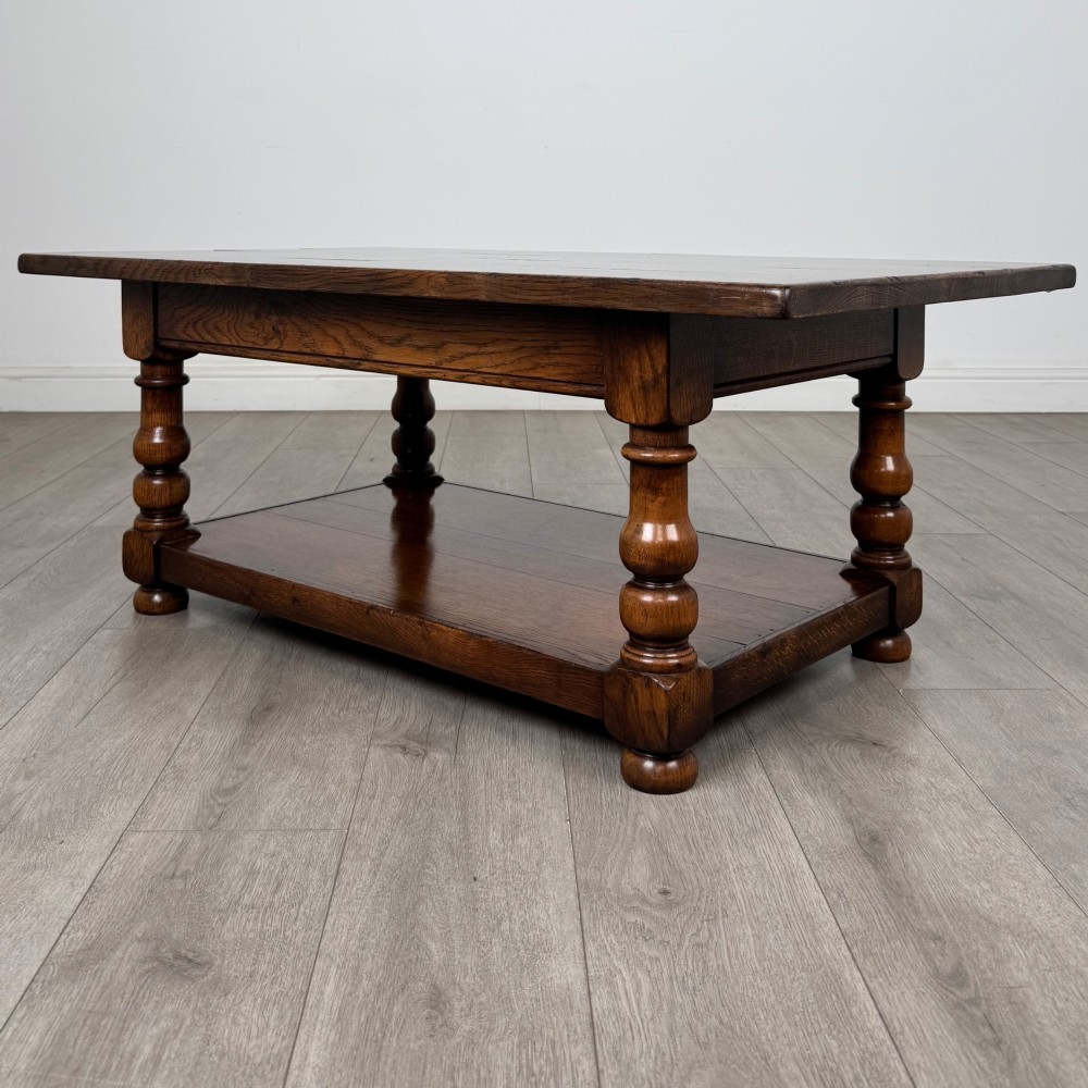 A rectangular dark oak coffee table featuring turned baluster legs and a full-length lower shelf. View II
