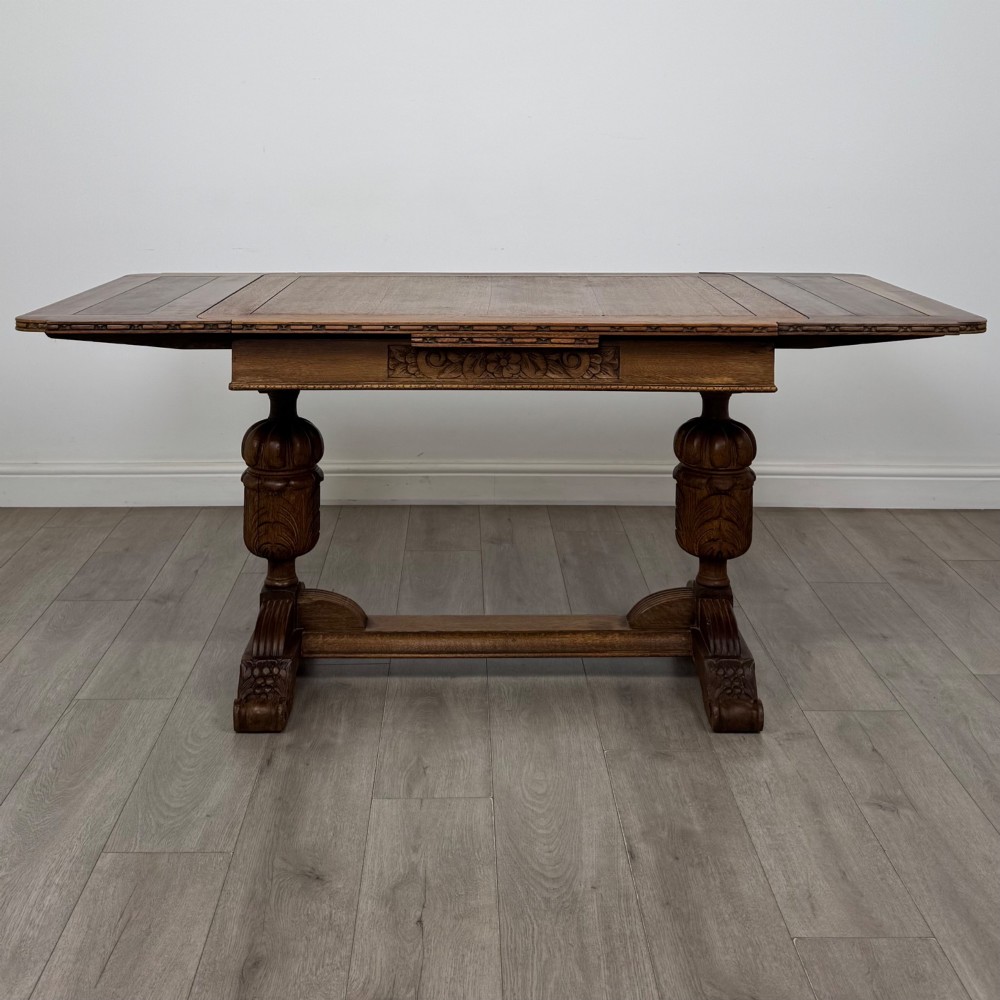 An antique Edwardian oak draw-leaf dining table featuring carved bulbous supports and a central stretcher. View II