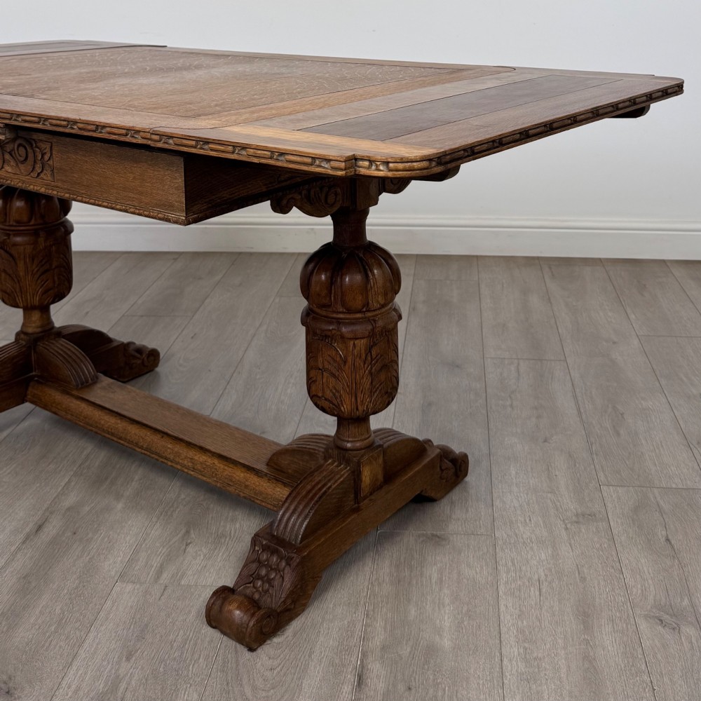 An antique Edwardian oak draw-leaf dining table featuring carved bulbous supports and a central stretcher. View VI