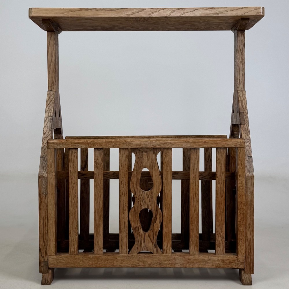 An antique Arts and Crafts oak side table featuring a rectangular top supported by slender uprights above a slatted lower magazine trough.
