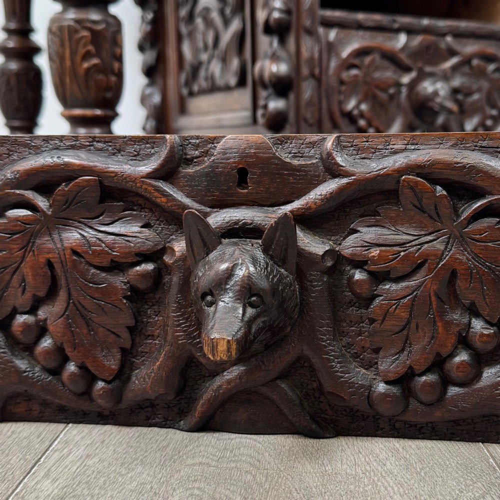 A 19th-century Victorian carved oak davenport desk featuring heavy foliate carvings, turned columns, and a green leather insert. View XII