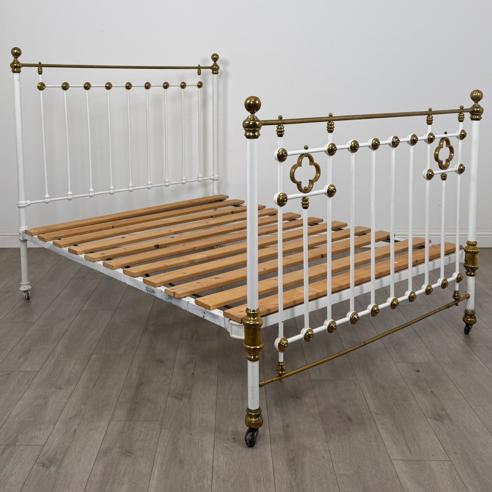 Victorian white-painted iron and polished brass king-size bedstead featuring round brass finials and quatrefoil metalwork. View II