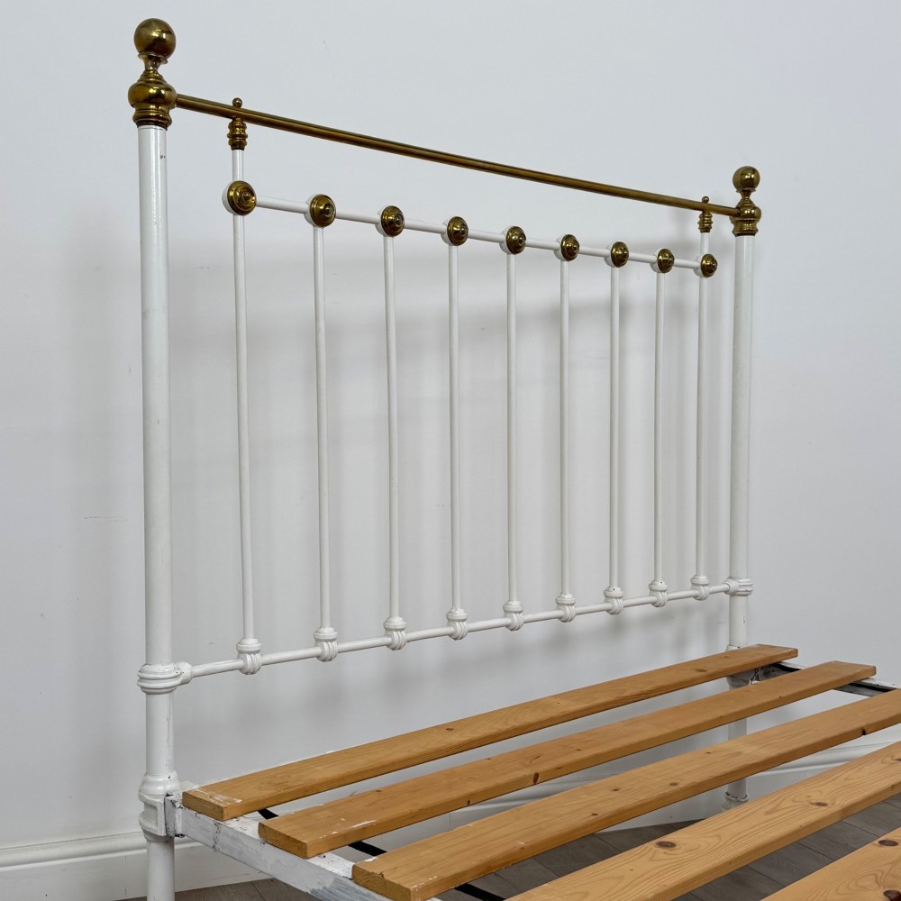 Victorian white-painted iron and polished brass king-size bedstead featuring round brass finials and quatrefoil metalwork. View V