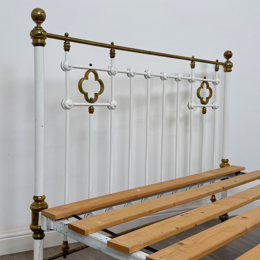 Victorian white-painted iron and polished brass king-size bedstead featuring round brass finials and quatrefoil metalwork. View VI