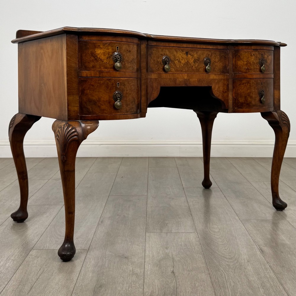 An Edwardian burr walnut writing table featuring five drawers with brass drop handles and carved cabriole legs. View VIII