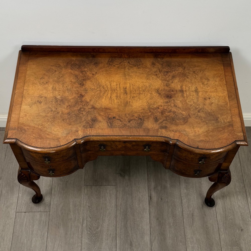 An Edwardian burr walnut writing table featuring five drawers with brass drop handles and carved cabriole legs. View IX