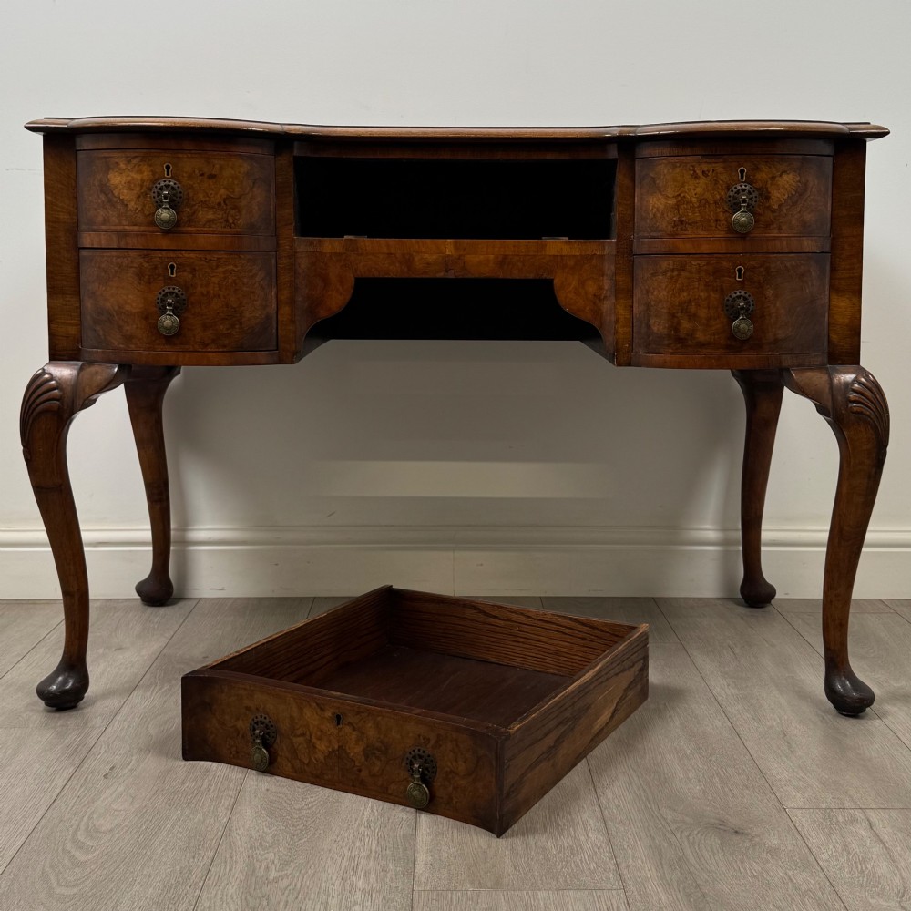 An Edwardian burr walnut writing table featuring five drawers with brass drop handles and carved cabriole legs. View X