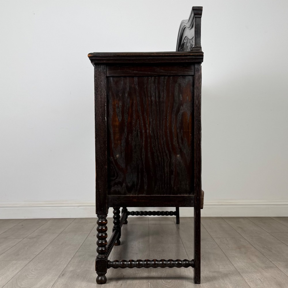 A dark oak 19th-century sideboard featuring carved lion mask motifs, scrollwork panel doors, and bobbin-turned legs connected by stretchers. View IV
