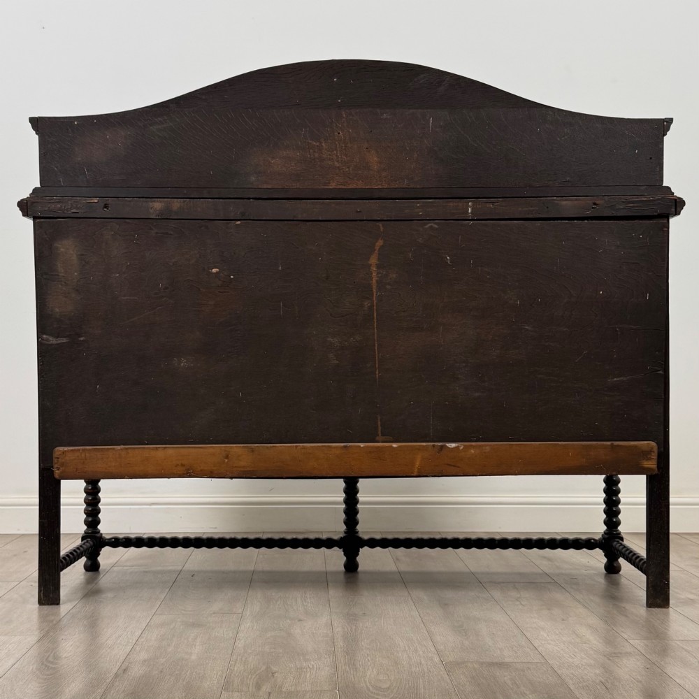 A dark oak 19th-century sideboard featuring carved lion mask motifs, scrollwork panel doors, and bobbin-turned legs connected by stretchers. View VI