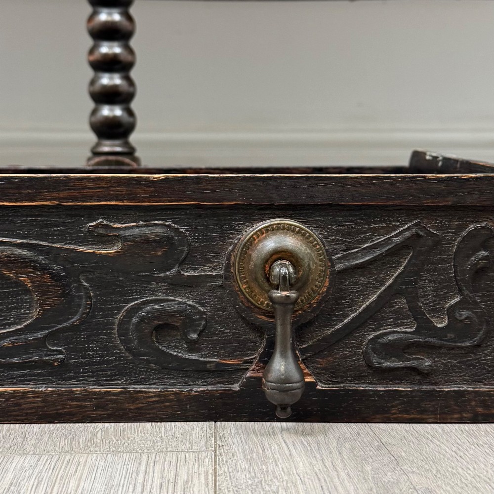 A dark oak 19th-century sideboard featuring carved lion mask motifs, scrollwork panel doors, and bobbin-turned legs connected by stretchers. View XII