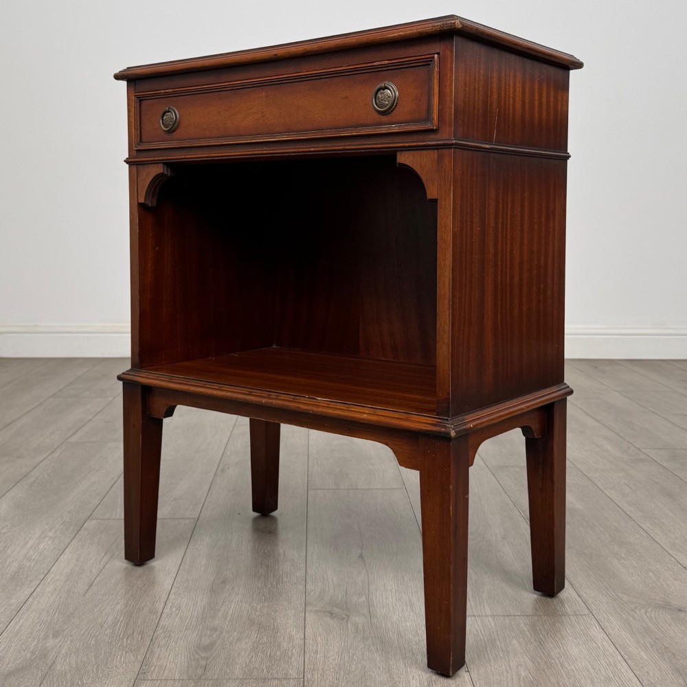 A small mahogany bedside cabinet with a top drawer, brass ring pull handles, an open lower shelf, and straight tapered legs. View II