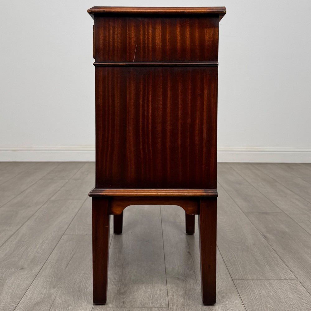 A small mahogany bedside cabinet with a top drawer, brass ring pull handles, an open lower shelf, and straight tapered legs. View III