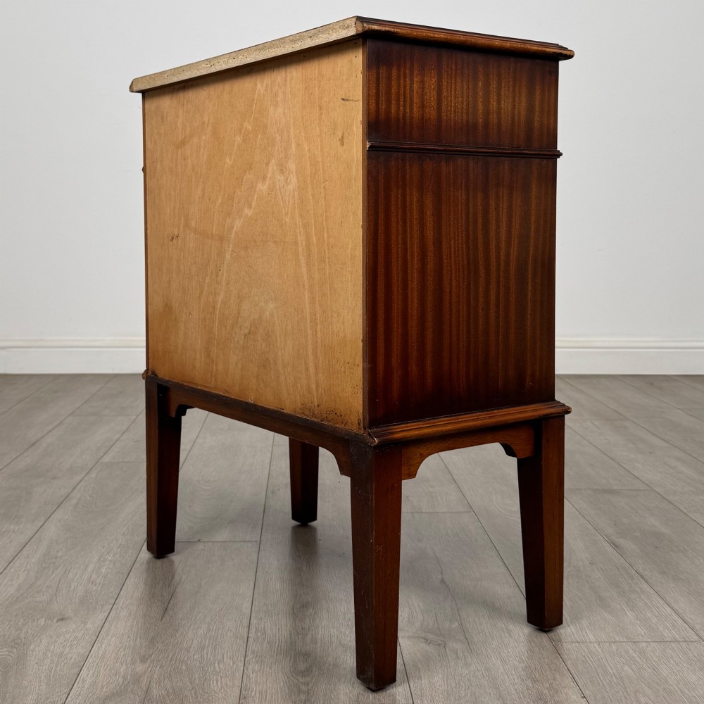 A small mahogany bedside cabinet with a top drawer, brass ring pull handles, an open lower shelf, and straight tapered legs. View VI