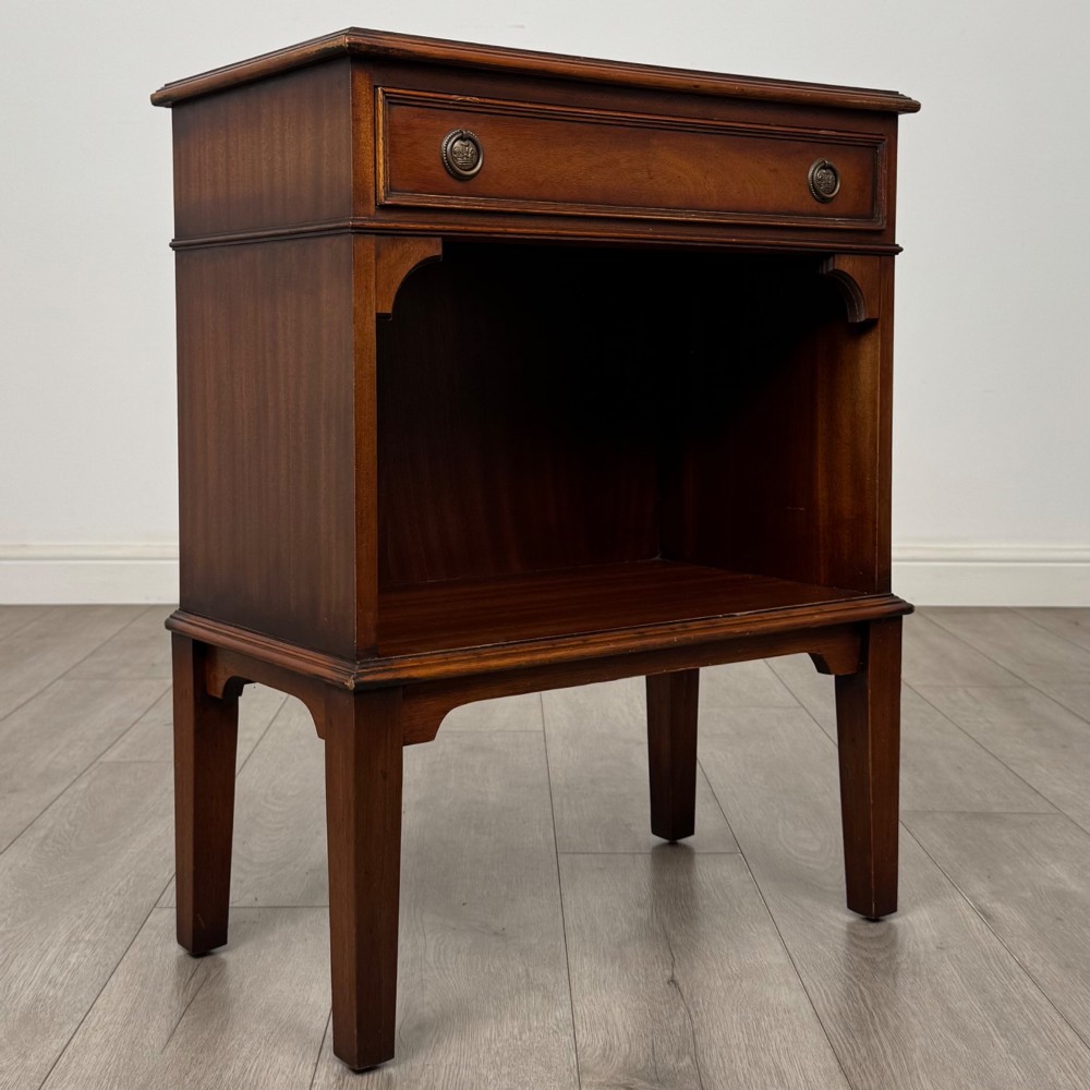 A small mahogany bedside cabinet with a top drawer, brass ring pull handles, an open lower shelf, and straight tapered legs. View VIII