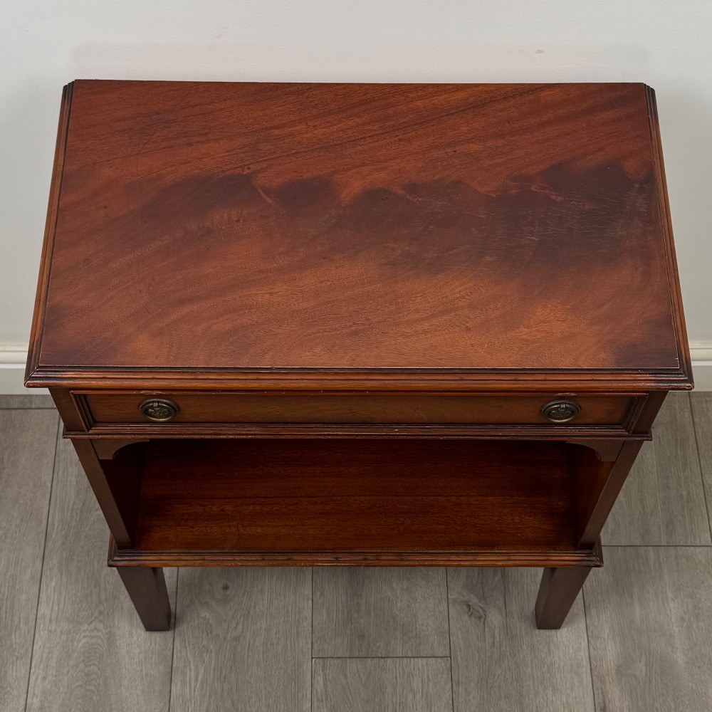 A small mahogany bedside cabinet with a top drawer, brass ring pull handles, an open lower shelf, and straight tapered legs. View IX