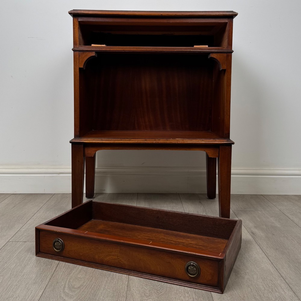 A small mahogany bedside cabinet with a top drawer, brass ring pull handles, an open lower shelf, and straight tapered legs. View X
