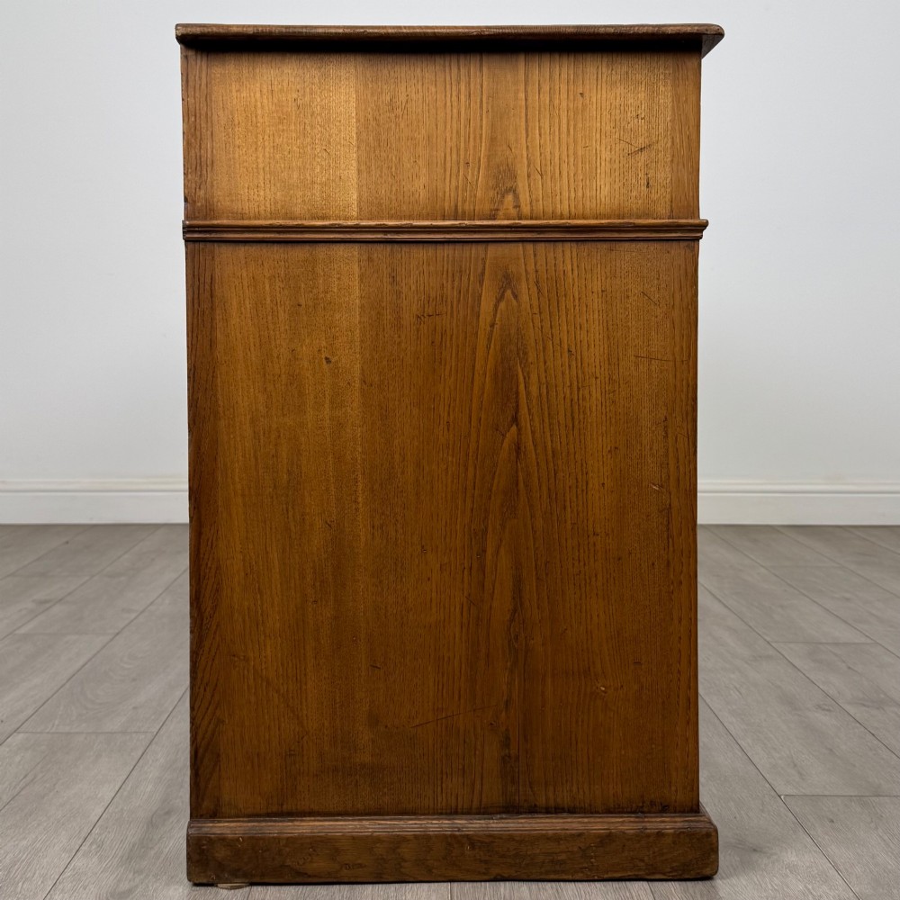 An antique golden oak dresser base featuring three top drawers, two panelled outer doors, and a central arched open recess. View VIII