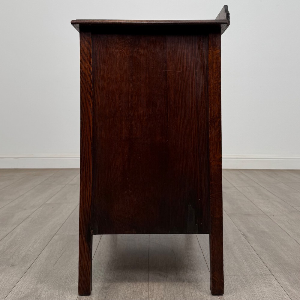 An Edwardian oak chest of drawers featuring three full-width drawers with circular pull handles, supported by straight square legs. View III