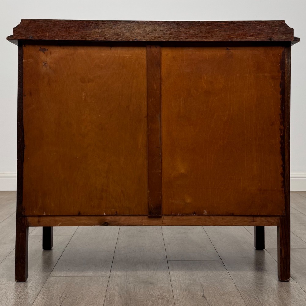 An Edwardian oak chest of drawers featuring three full-width drawers with circular pull handles, supported by straight square legs. View V