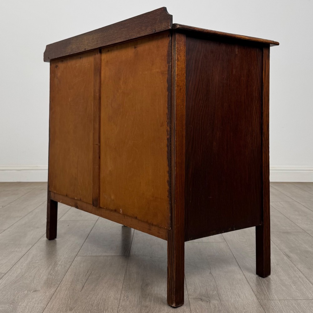 An Edwardian oak chest of drawers featuring three full-width drawers with circular pull handles, supported by straight square legs. View VI