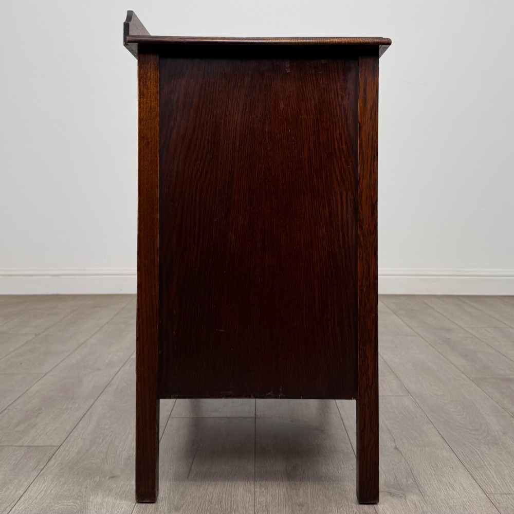 An Edwardian oak chest of drawers featuring three full-width drawers with circular pull handles, supported by straight square legs. View VII