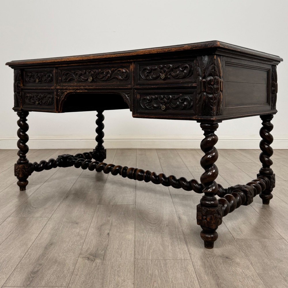 A 19th-century dark oak writing table featuring carved drawer fronts, barley twist legs, and a low spiral stretcher. View II