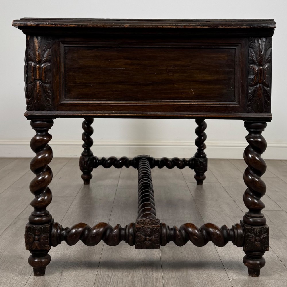 A 19th-century dark oak writing table featuring carved drawer fronts, barley twist legs, and a low spiral stretcher. View III
