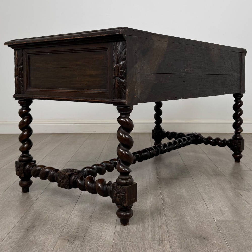 A 19th-century dark oak writing table featuring carved drawer fronts, barley twist legs, and a low spiral stretcher. View IV