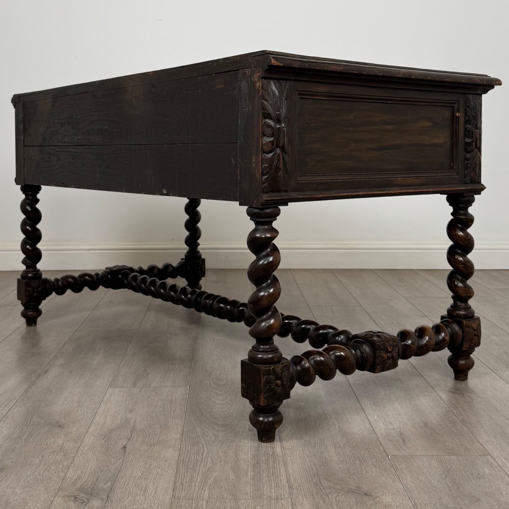 A 19th-century dark oak writing table featuring carved drawer fronts, barley twist legs, and a low spiral stretcher. View VI