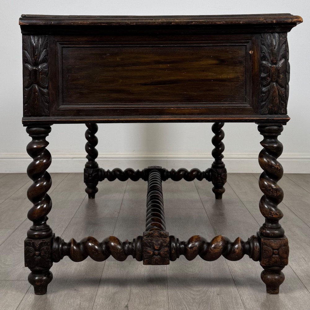 A 19th-century dark oak writing table featuring carved drawer fronts, barley twist legs, and a low spiral stretcher. View VII