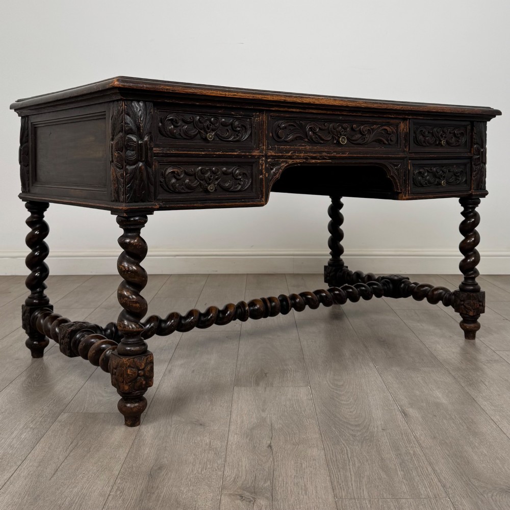 A 19th-century dark oak writing table featuring carved drawer fronts, barley twist legs, and a low spiral stretcher. View VIII