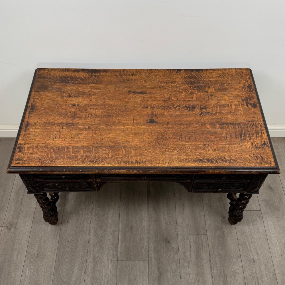 A 19th-century dark oak writing table featuring carved drawer fronts, barley twist legs, and a low spiral stretcher. View IX